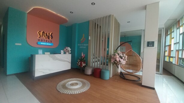 Zona de recepció d'hotel amb un disseny modern, que inclou una taula de recepció, una cadira penjant i una paret decorativa.