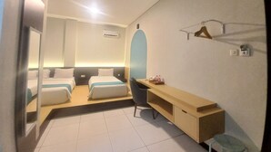 Habitació d'hotel amb dos llits, un escriptori, una cadira, un mirall, una perxa penjant i un aparell d'aire condicionat.