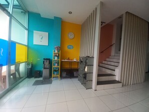 A modern interior with a staircase, a clock, and a water dispenser. - Collection O near Paragon City Mall Sema (Semarang)