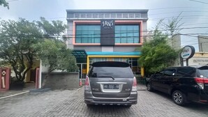 Un edifici amb un cartell que diu 'SANS HOTELS' i una SUV estacionada al davant.