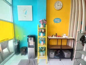 A room with a water dispenser, a clock, a shelf with flowers, and a sign saying 'GRAB YOUR COFFEE HERE'. - Collection O near Paragon City Mall Sema (Semarang)
