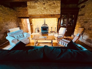 Ein gemütlicher Raum mit Steinwand, Kamin, Sofa und Sessel.