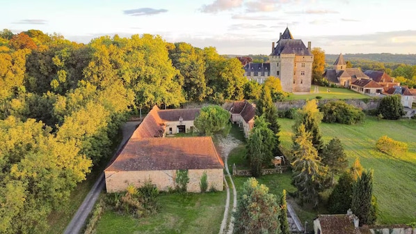 Eine Burg, umgeben von Bäumen und ein kleines Gebäude mit rotem Dach.