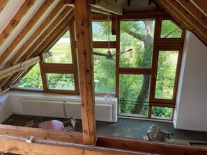 A room with a sloped ceiling, large windows, a radiator, and a chair. - Charming hideaway - nature, wine and sunsets (Traben-Trarbach)