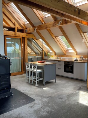 A kitchen with a skylight, wooden beams, a dining area with chairs, and a refrigerator. - Charming hideaway - nature, wine and sunsets (Traben-Trarbach)