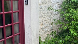 A stone wall with a red-framed window and a small outdoor light fixture. - Maison de la Couturière (Collan)