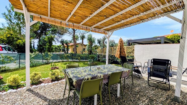 An outdoor patio with a table and chairs, a grill, and a pergola.