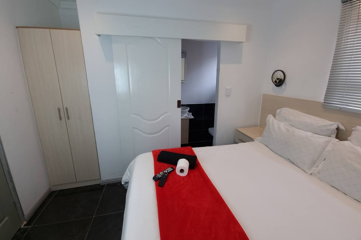 A hotel room with a bed, a wardrobe, a bathroom, and a window with blinds.