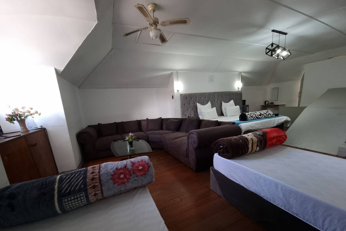 A modern room with a sofa, a bed, a small table, and a ceiling fan.