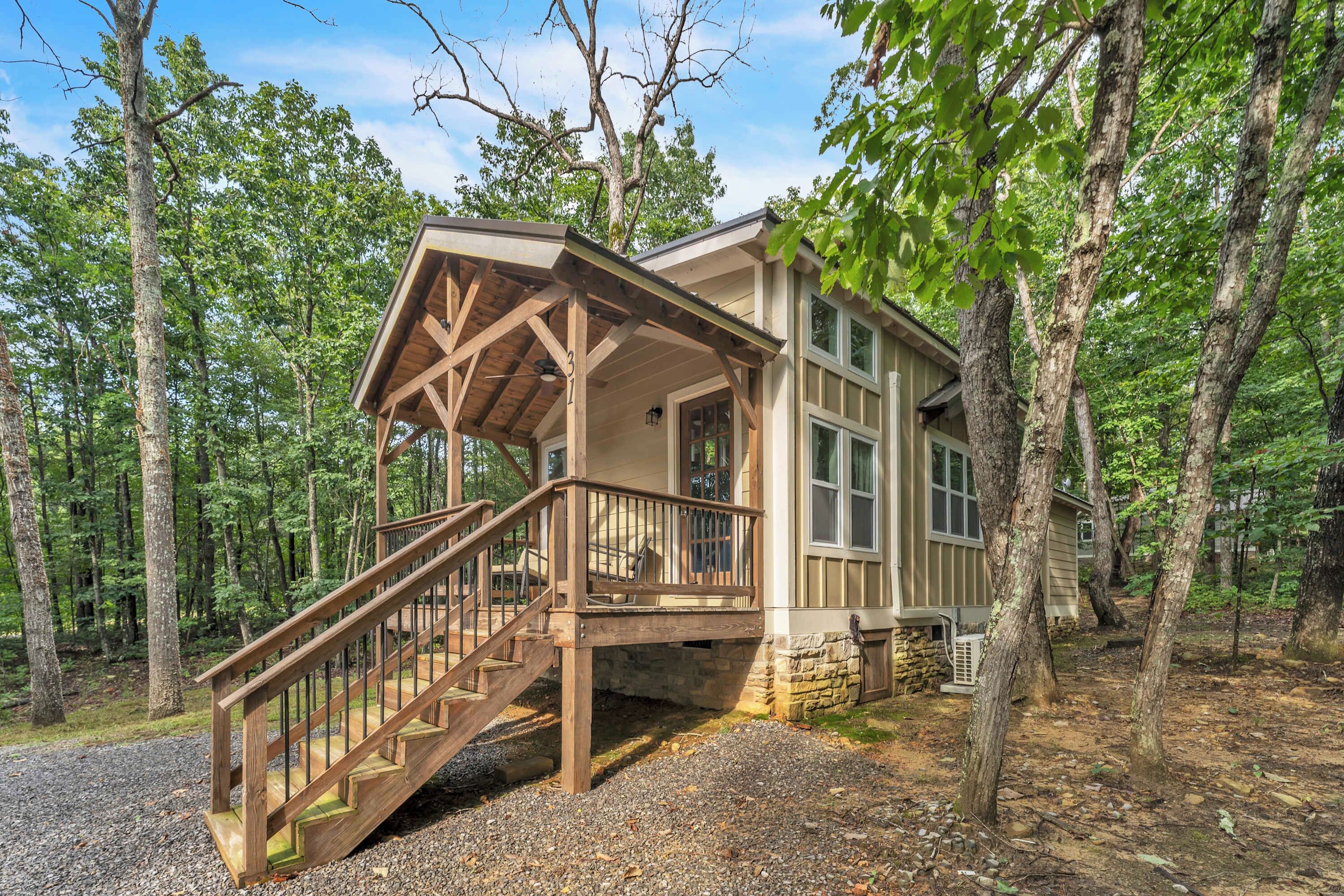 A cabin with a wooden staircase leading to a porch, surrounded by trees.