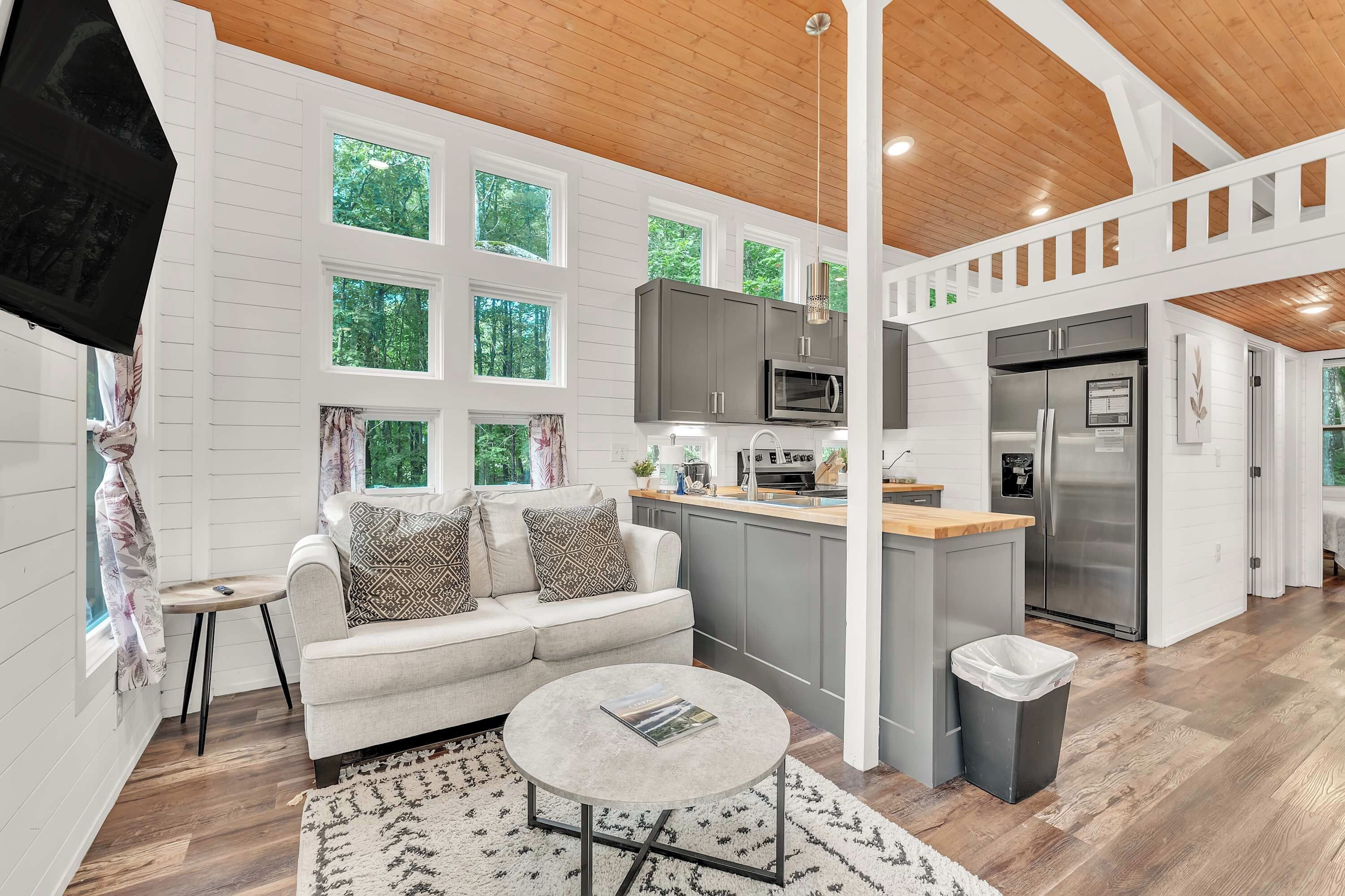 A modern kitchen with grey cabinets, a stainless steel refrigerator, and a microwave.
