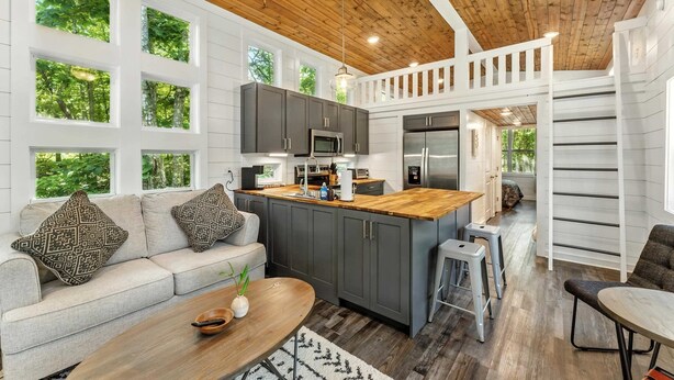 A modern kitchen with grey cabinets, a wooden island, and a built-in oven.