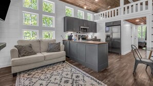 A modern kitchen with grey cabinets, a central island, and a dining area with a chair.