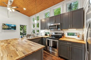 Una cocina moderna con una isla de madera, electrodomésticos de acero inoxidable y ventanas amplias.