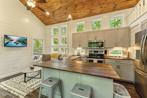 A modern kitchen with a wooden ceiling, large windows, and stainless steel appliances. - Family getaway in Menlo, GA (Menlo)