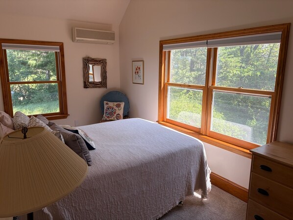 Quarto com cama, penteadeira, abajur, espelho e um quadro na parede.