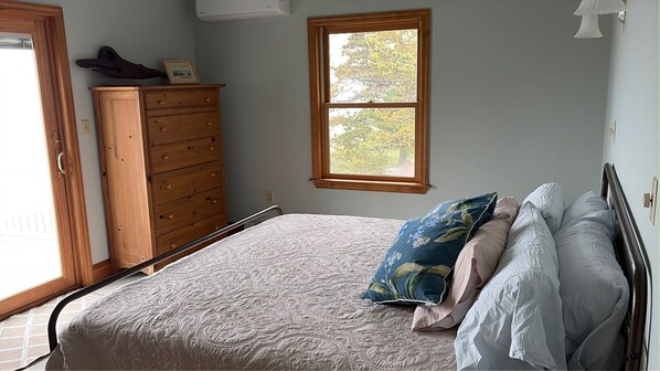 A bedroom with a bed, a dresser, a window, and a door. - Stunning 4BR Ontario Lake House (Mannsville)
