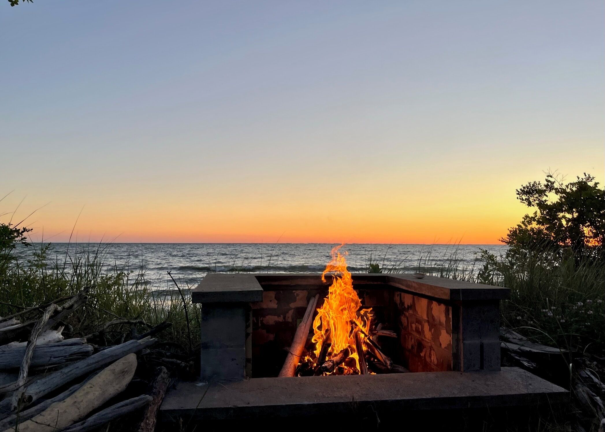 A fire pit with a view of the ocean at sunset.