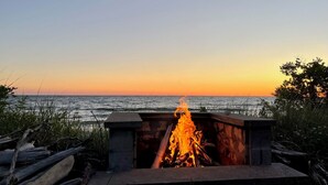 Ein Lagerfeuer mit Blick auf den Ozean bei Sonnenuntergang.