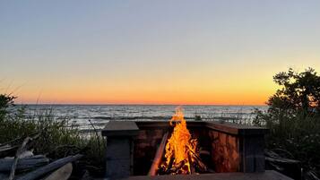 A fire pit with a view of the ocean at sunset.
