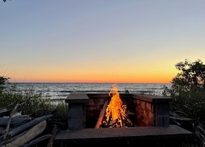 A fire pit with a view of the ocean at sunset. - Stunning 4BR Ontario Lake House (Mannsville)