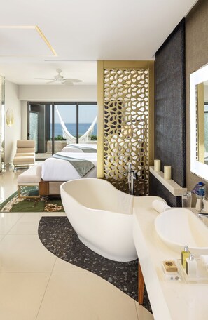 Ein modernes Badezimmer mit freistehender Badewanne, einem großen Spiegel und Meerblick.