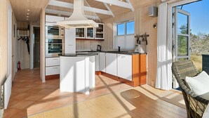 Eine moderne Küche mit weißen Schränken, einer zentralen Kochinsel und einem großen Fenster.