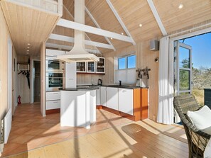 Une cuisine moderne avec des meubles blancs, un îlot central et une grande fenêtre.