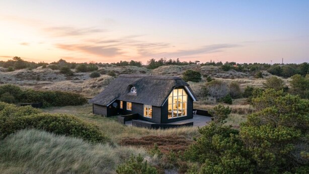 Ein Haus mit einem großen Fenster, umgeben von einer natürlichen Landschaft.