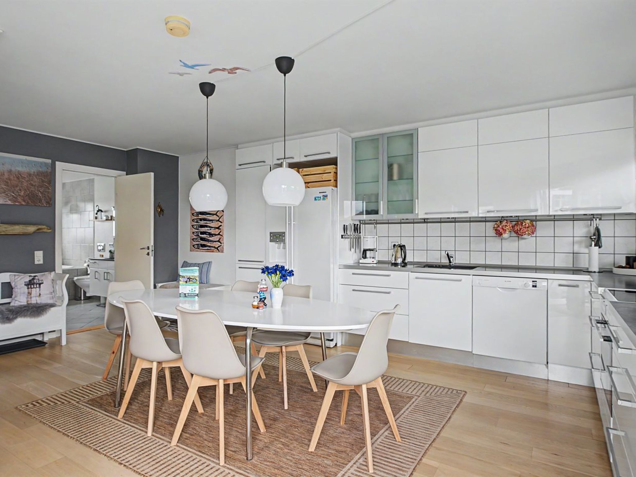 A modern kitchen with white cabinets, a central island, and pendant lighting.