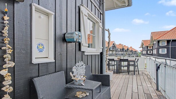 A wooden deck with outdoor seating, a mailbox, and a view of neighboring houses.