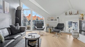 A modern living room with a leather sofa, a round coffee table, and two black chairs.