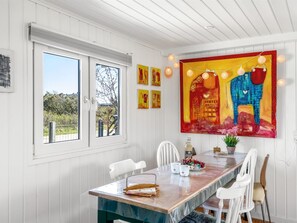 Ein Essbereich mit einem langen Tisch, Stühlen und einem Bild an der Wand.
