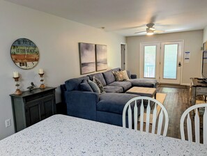 Ein Wohnzimmer mit einer Eckcouch, einem Esstisch und einer Küchenzeile.