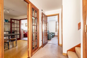 A hallway with a kitchen area, a dining table, and a seating area with sofas. - Sahara Park (No 11) | Elie (Elie)