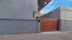 Un bâtiment moderne à la façade grise, doté d’un portail en bois et d’une allée d’entrée pavée.