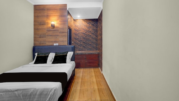 Une chambre à coucher avec un lit, une table de chevet, une lampe fixée au mur et un mur en briques.