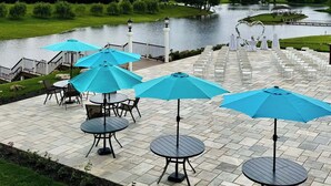 A patio with tables and blue umbrellas overlooking a body of water. - Peaceful Lakefront 1BR 1 Full Bath w/ Private Island Access & Breakfast Included (Purcellville)