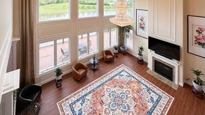 A spacious living room with large windows, a fireplace, and a large rug. - Peaceful Lakefront 1BR 1 Full Bath w/ Private Island Access & Breakfast Included (Purcellville)