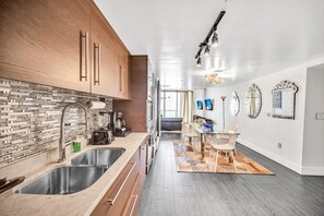 A modern kitchen with a brick backsplash, stainless steel appliances, and a dining area with a rug and chairs. - Icon Brickell - 19th Fl - Oceanview - Spa Access (Miami)