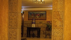 A lobby with stone columns, a chandelier, a painting, and a water dispenser. - Cerro Rico Hotel with Garage - Breakfast Included (Villa Imperial de Potosí)