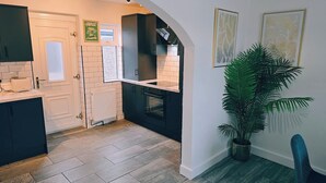 Een keuken met een witte betegelde spatwand, een zwarte oven en een potplant.