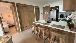 Una cocina moderna con armarios de madera, un refrigerador de acero inoxidable, un lavamanos doble y taburetes de bar.