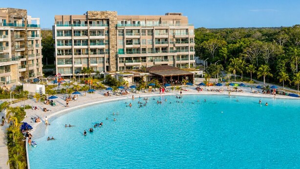 Un resort con una piscina grande, varias construcciones y una zona de playa.