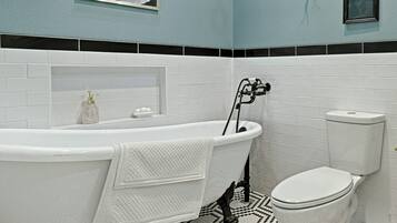 Et badeværelse med et fristående badekar, toilet og håndvask.