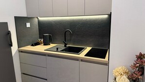 A compact kitchen with a black countertop, a sink, and a coffee maker. - Cozy 1-bedroom building apartment in welcoming Kostajnica with AC (Kostajnica)