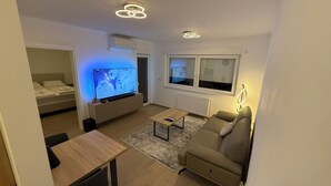 A modern living room with a flat-screen TV, a sofa, a coffee table, and a dining area. - Cozy 1-bedroom building apartment in welcoming Kostajnica with AC (Kostajnica)