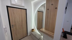 A hallway with wooden doors, a mirror, and a small table with a vase. - Cozy 1-bedroom building apartment in welcoming Kostajnica with AC (Kostajnica)