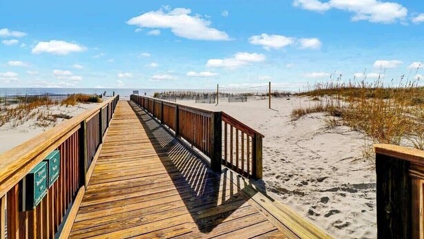 A wooden boardwalk leading to a beach with sand dunes and a clear sky. - Modern Ocean Oasis - Private Beach • Pool • OceanViews (Hilton Head Island)