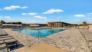 A swimming pool with lounge chairs and a building in the background. - Modern Ocean Oasis - Private Beach • Pool • OceanViews (Hilton Head Island)